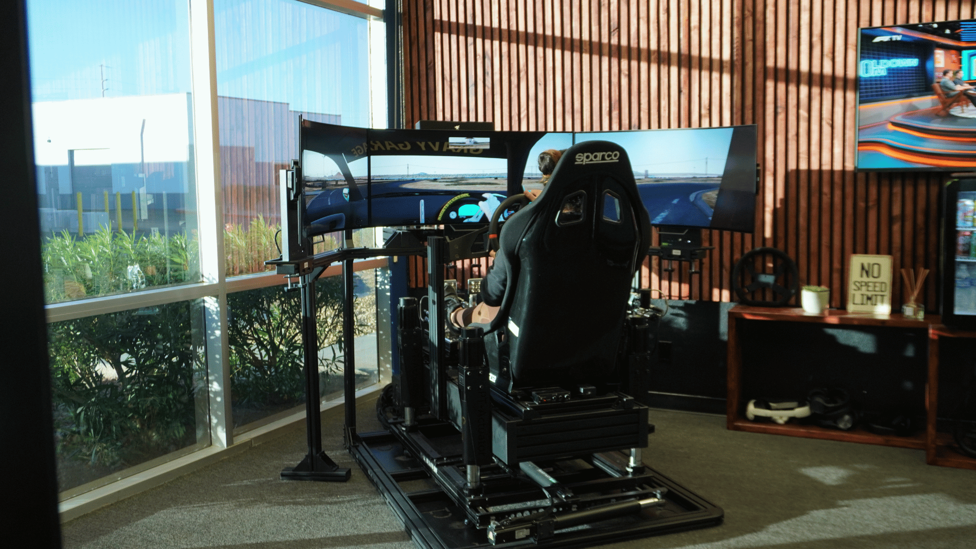Elite 6DOF motion racing simulator with black aluminum frame and blue hydraulic pedals in turnkey setup